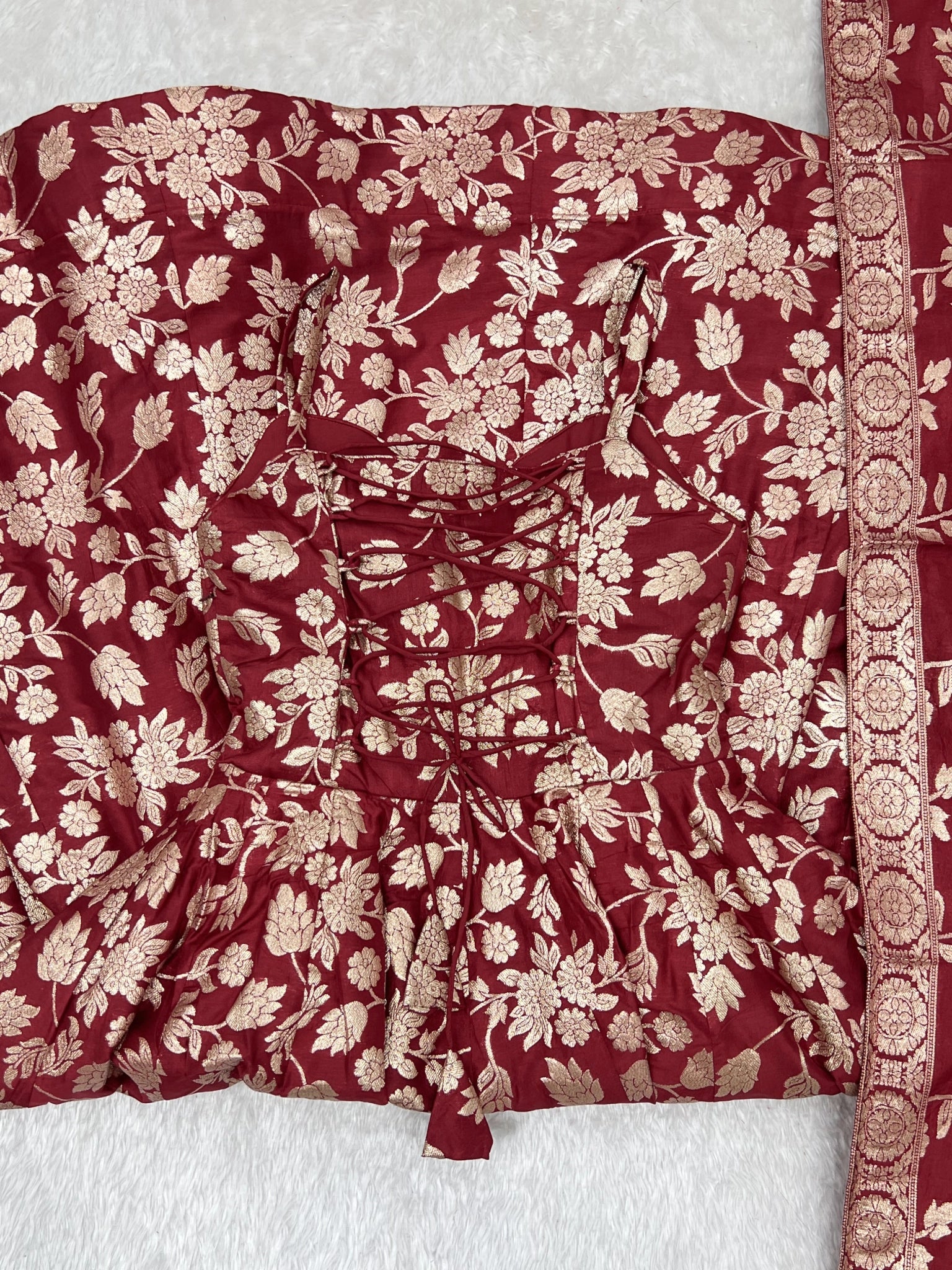 Close-up of lace-up dori back and Banarasi jacquard weave on maroon suit