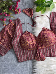 Maroon multicolor printed padded blouse with geometric and floral patterns, displayed on a white fur surface with artificial flowers and green leaves in the background.