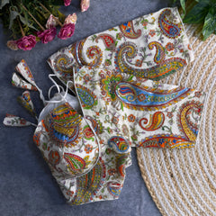 Multicolor paisley embroidered padded blouse with tie-up detail, displayed on a grey surface with artificial pink flowers and green leaves in the background.