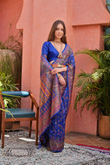  Woman wearing navy blue Kashmiri Jal weaving saree with intricate patterns in a lush green outdoor backdrop