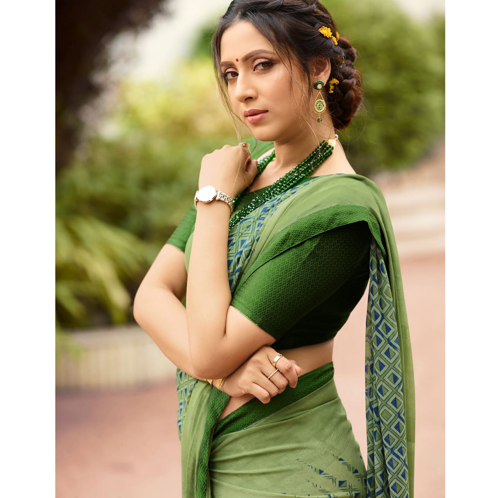 Woman in an olivine jacquard work saree with gold border standing indoors in an elegant room with arched decor and vintage furniture elements