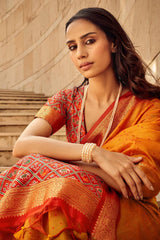 Close-up of woman wearing orange red saree with detailed zari work and patterned blouse, showcasing ethnic elegance and traditional Indian fashion