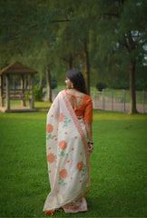 Back view of woman wearing orange resham weaving saree with floral motifs in garden setting