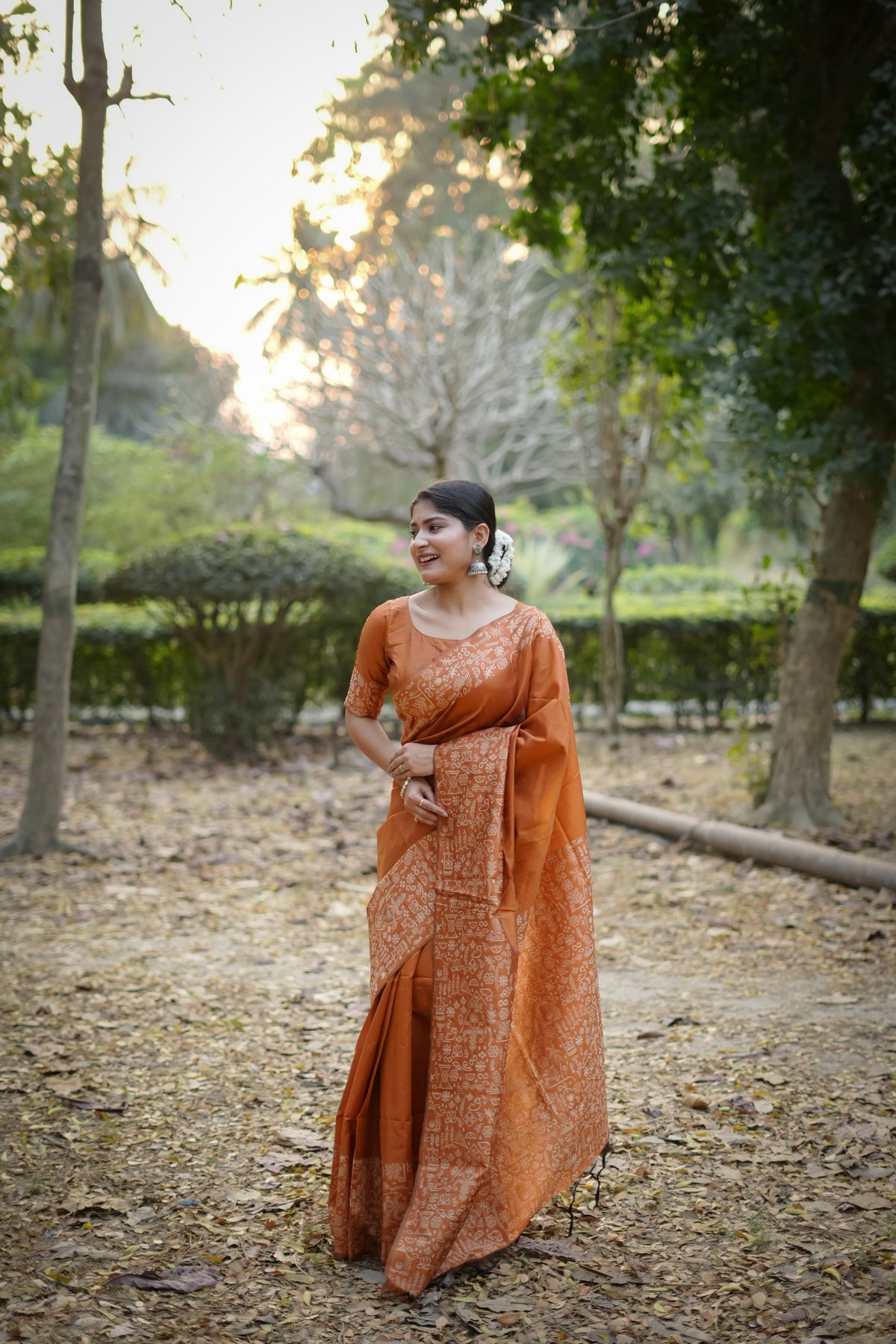 Orange saree with zari work in an outdoor setting