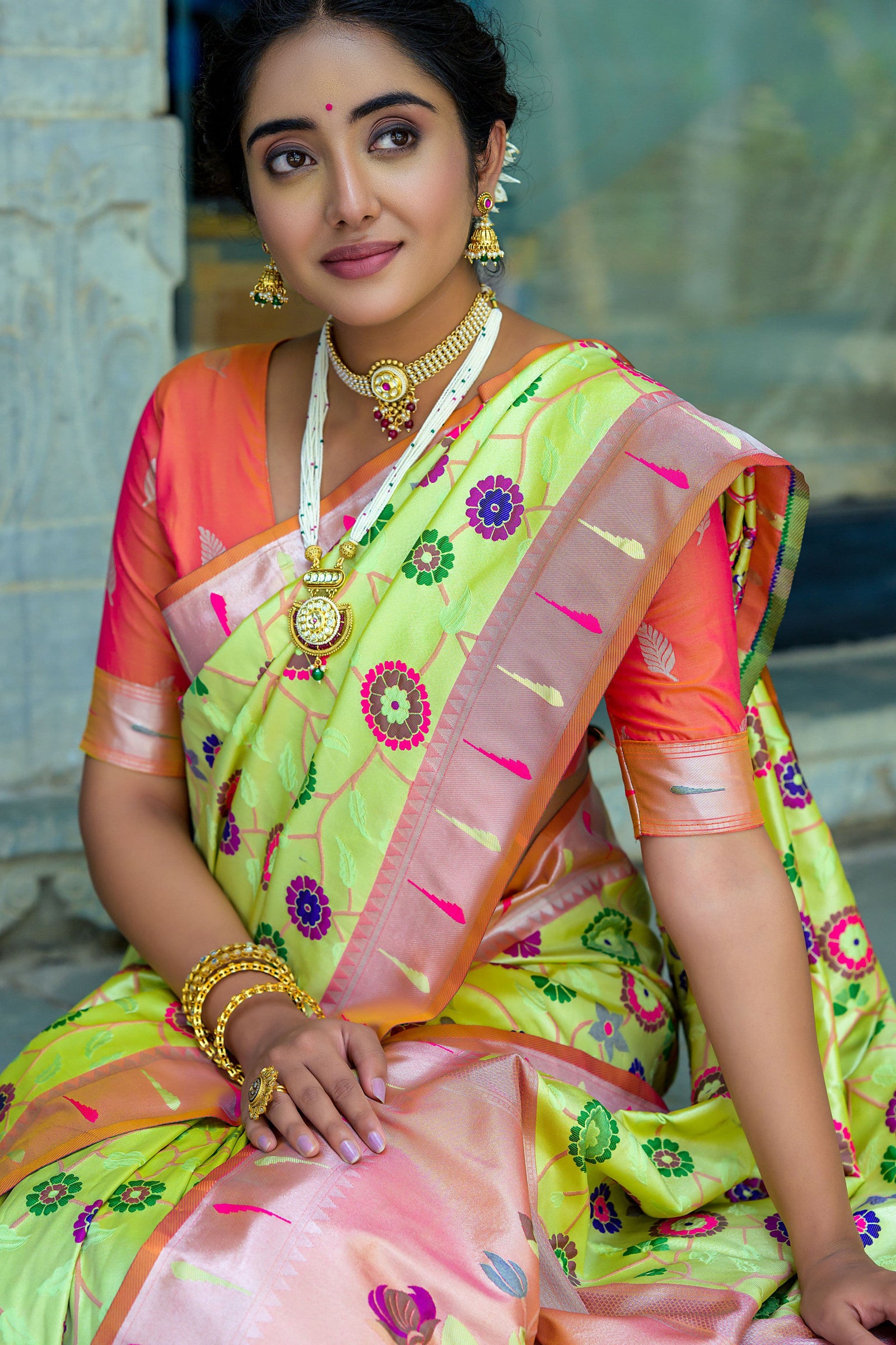 Close-up of woman in pastel pistachio green zari work saree with peach blouse and traditional gold jewelry
