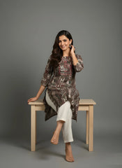 Woman sitting on a wooden bench wearing a patterned outfit against a gray background