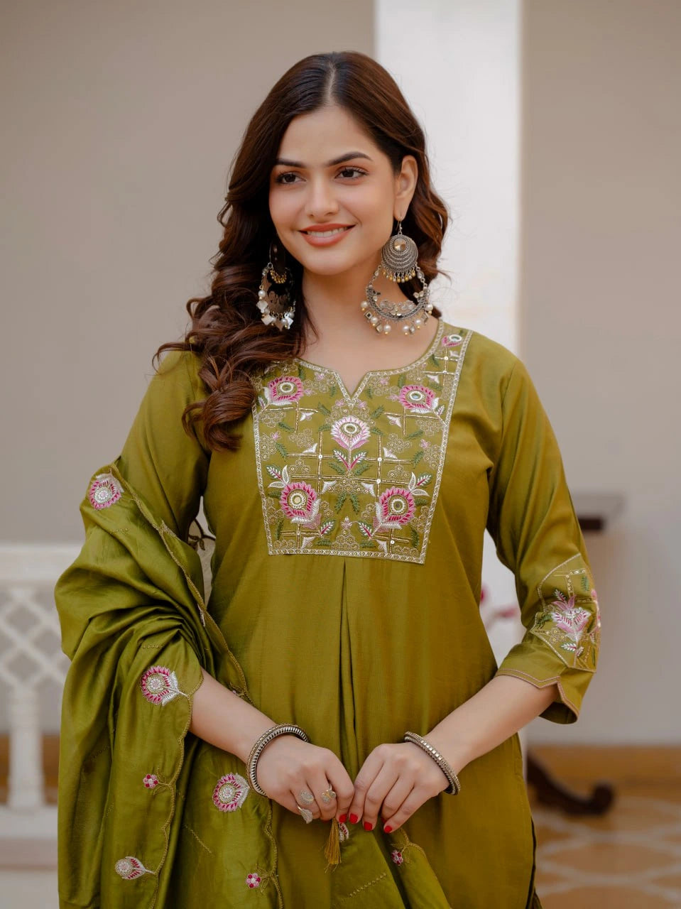 Woman wearing a green embroidered traditional outfit indoors