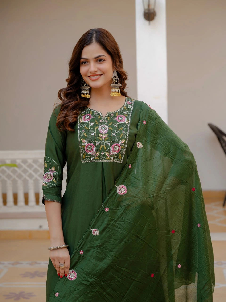 Woman wearing a green embroidered traditional outfit indoors