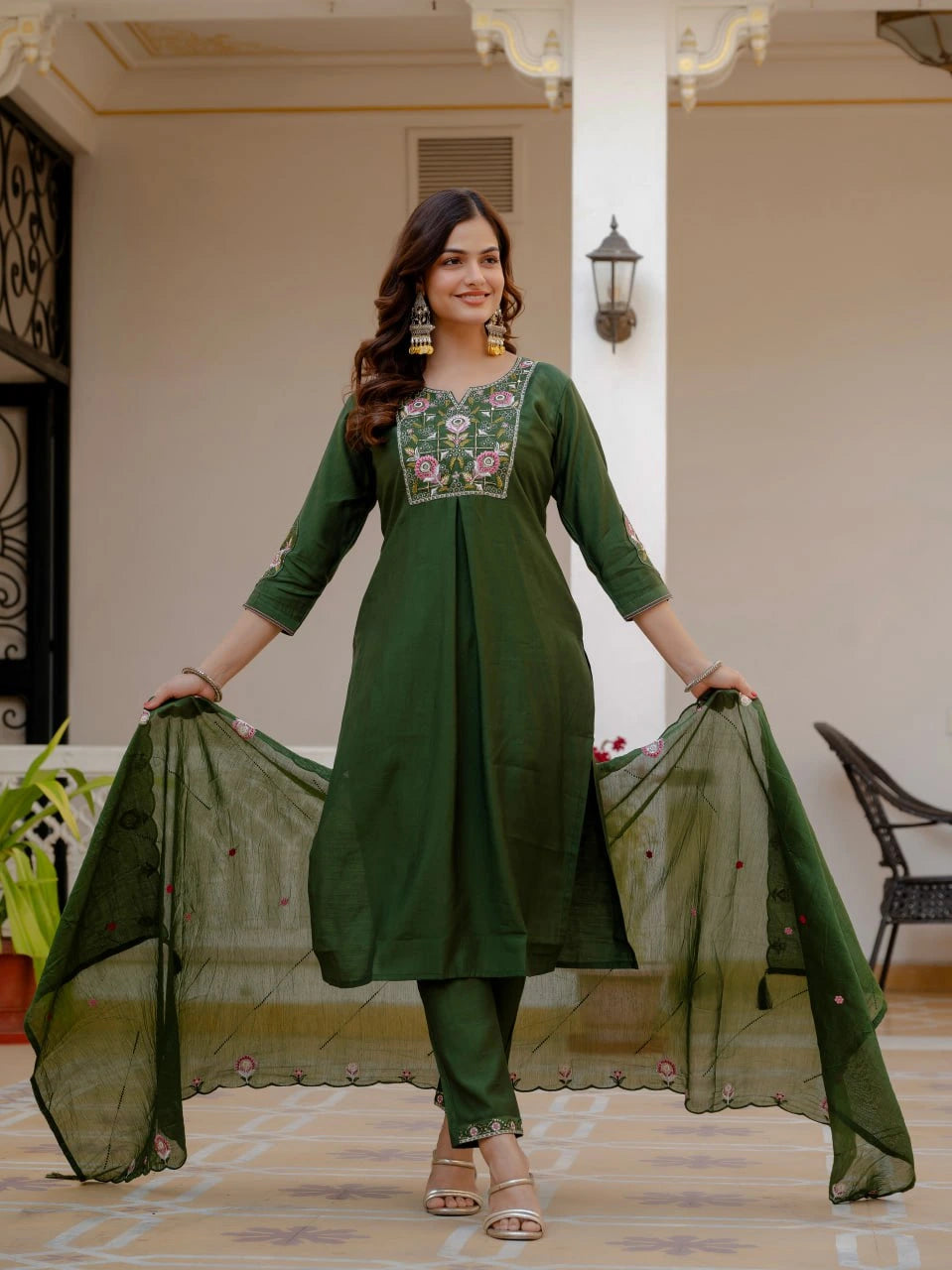 Woman wearing a green traditional outfit with embroidery in an indoor setting.