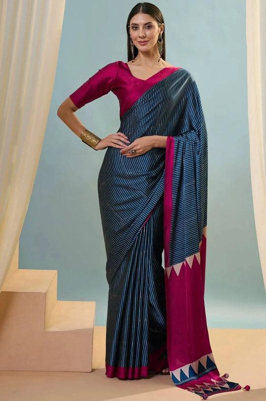 Woman wearing a blue and pink saree with a plain background