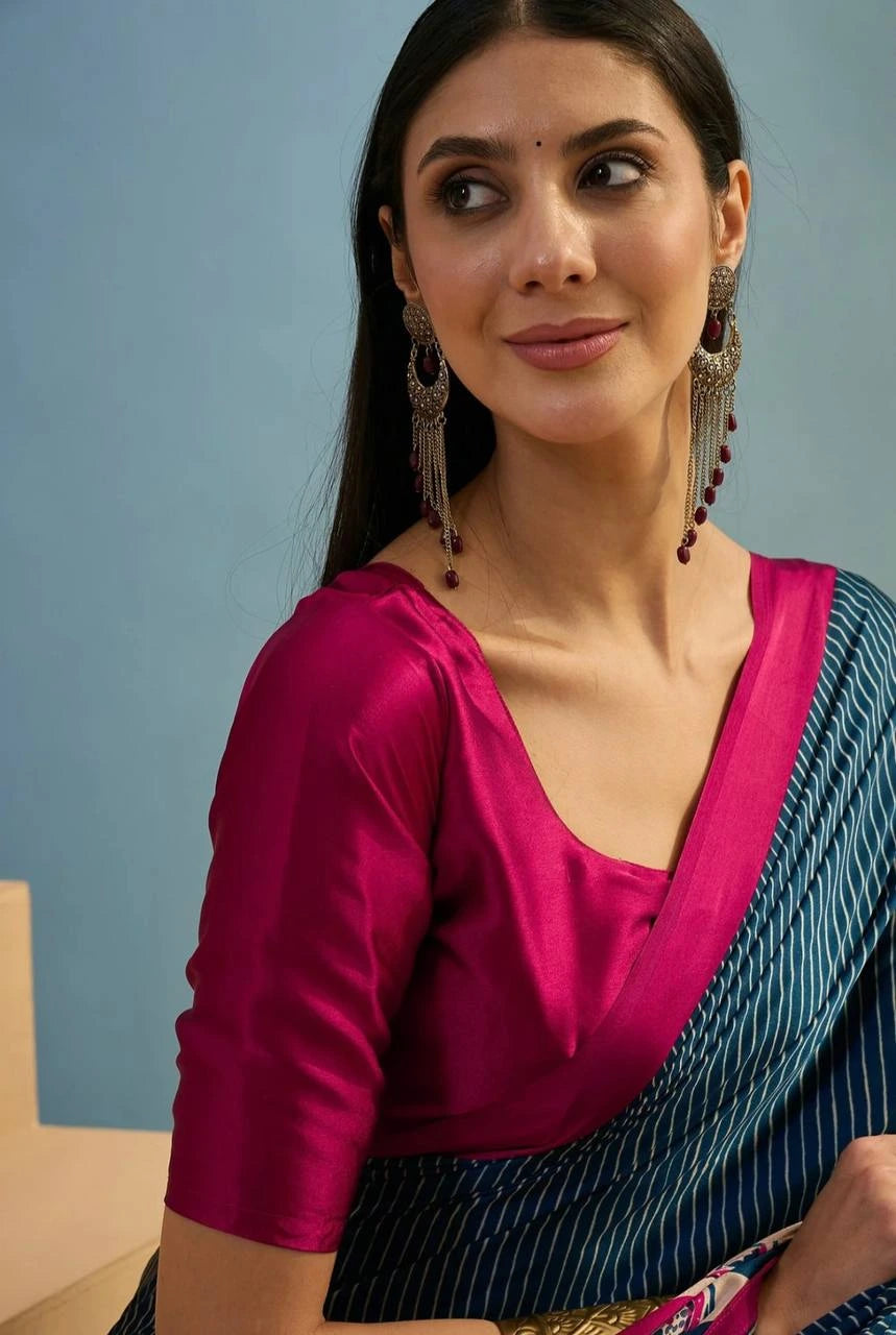 Woman wearing a pink blouse and blue saree against a light blue background