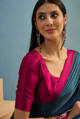 Woman wearing a pink blouse and blue saree against a light blue background