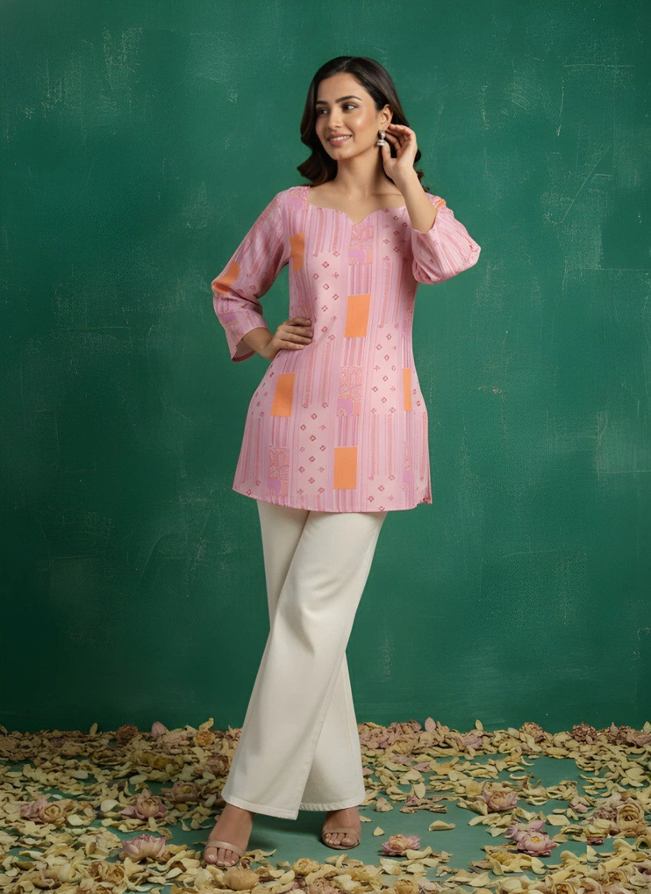 Woman wearing a pink patterned top and white pants against a green background