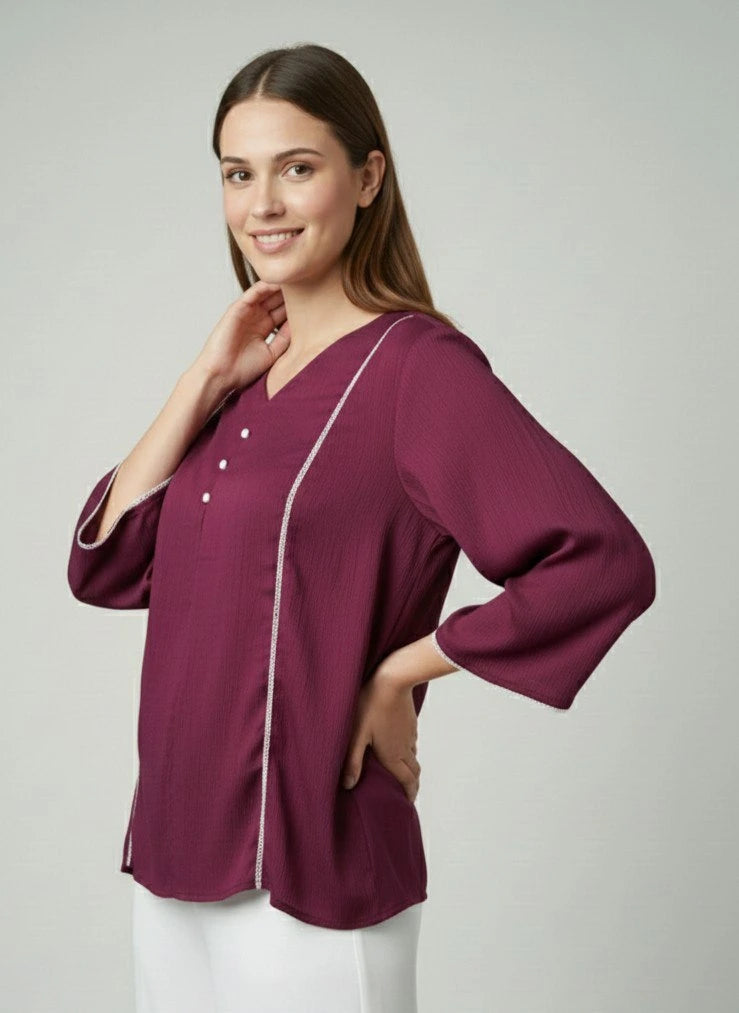 Woman wearing a maroon blouse with white trim on a plain background