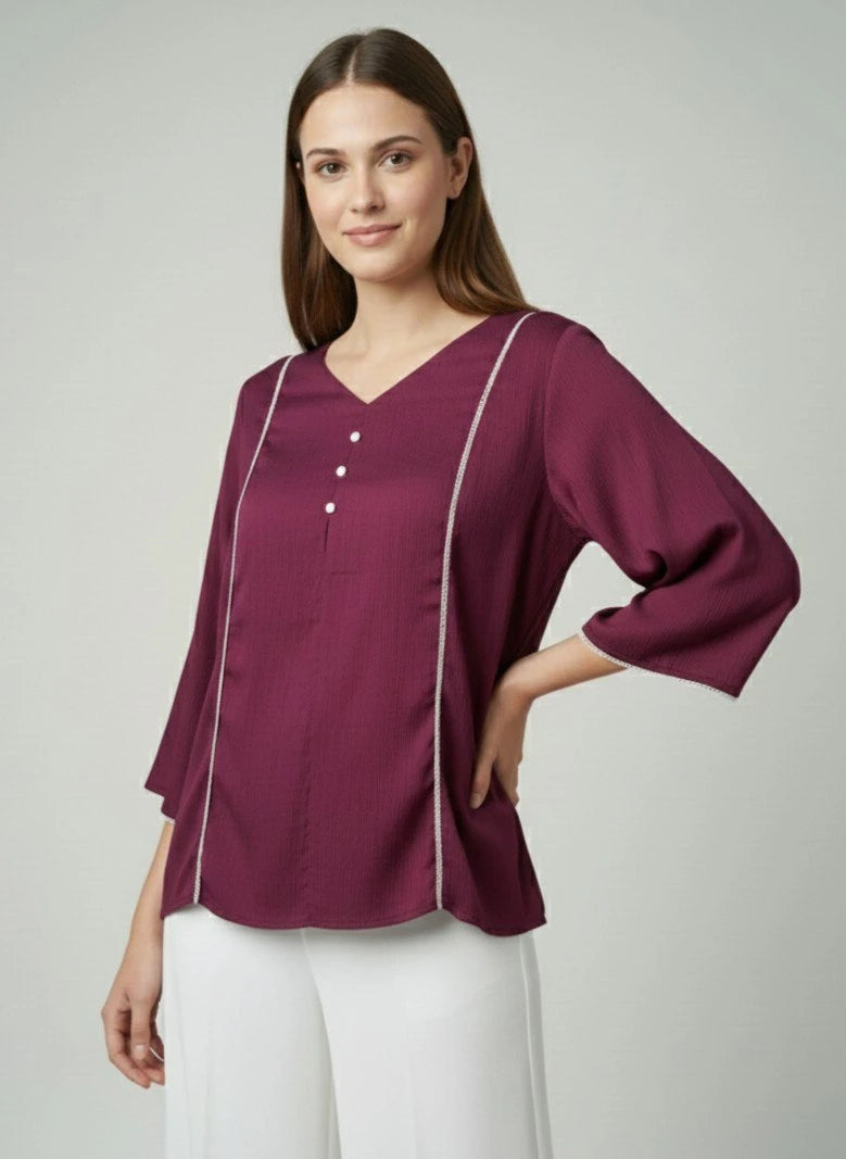 Woman wearing a purple blouse with white trim on a plain background