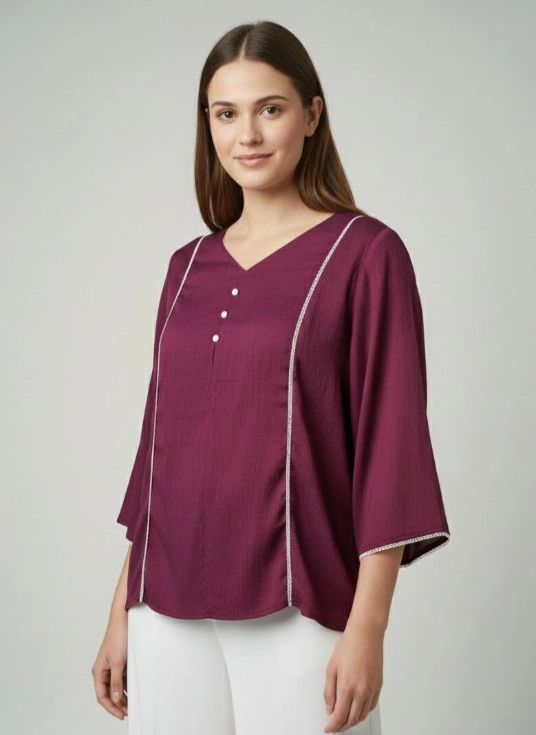 Woman wearing a purple blouse with white trim on a plain background