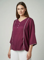 Woman wearing a purple blouse with white trim on a plain background