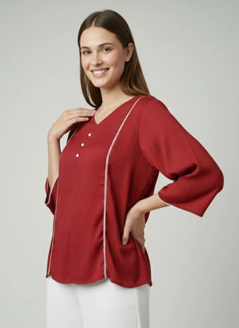 Woman wearing a red blouse with white trim on a plain background
