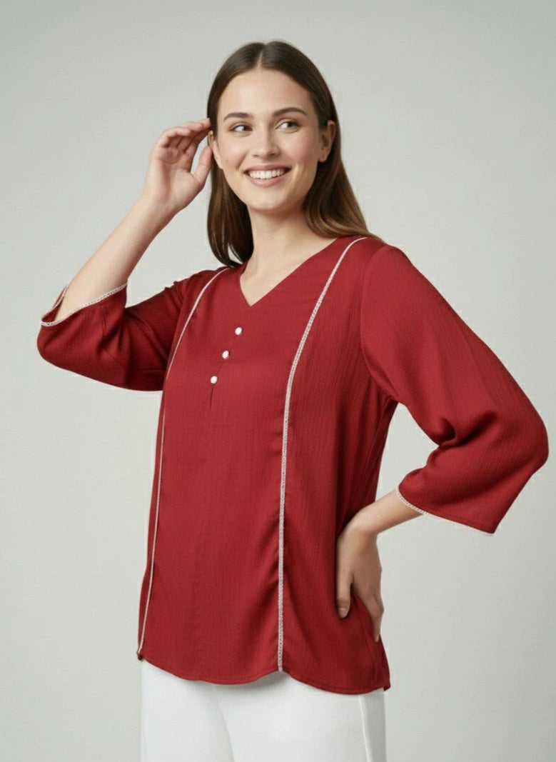 Woman wearing a red blouse with white trim on a plain background