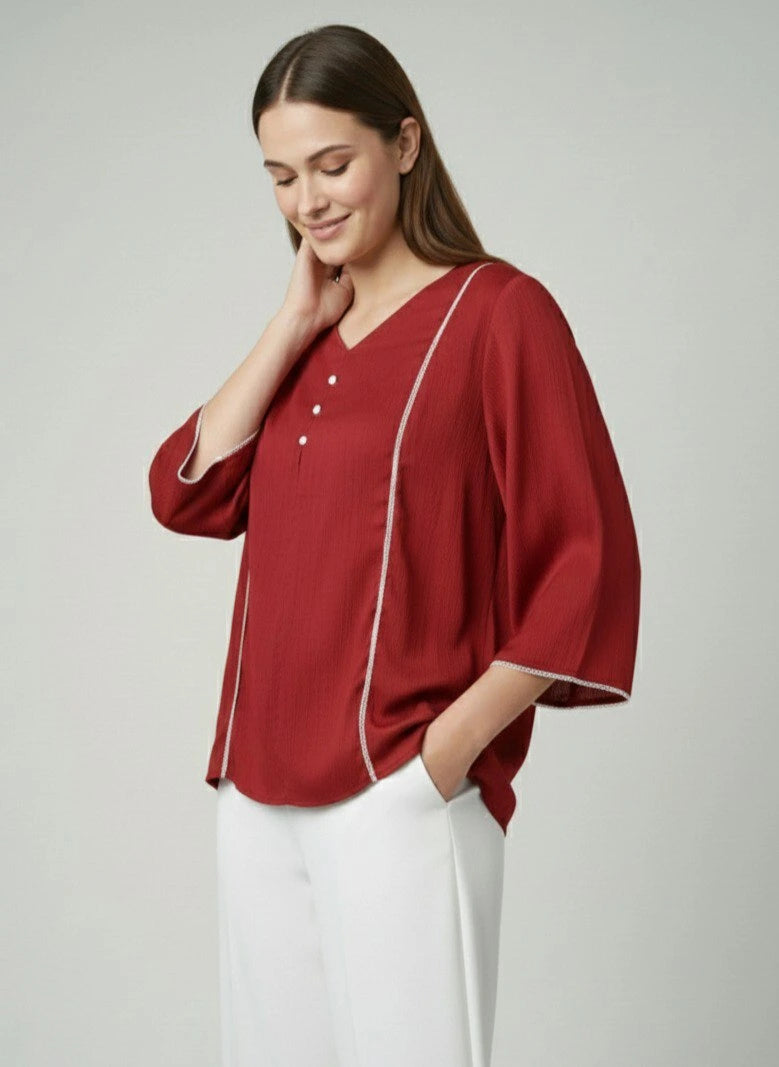 Woman wearing a red blouse with white trim on a plain background