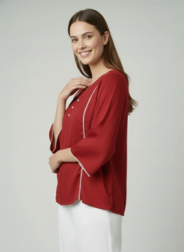 Woman wearing a red blouse with white trim on a plain background