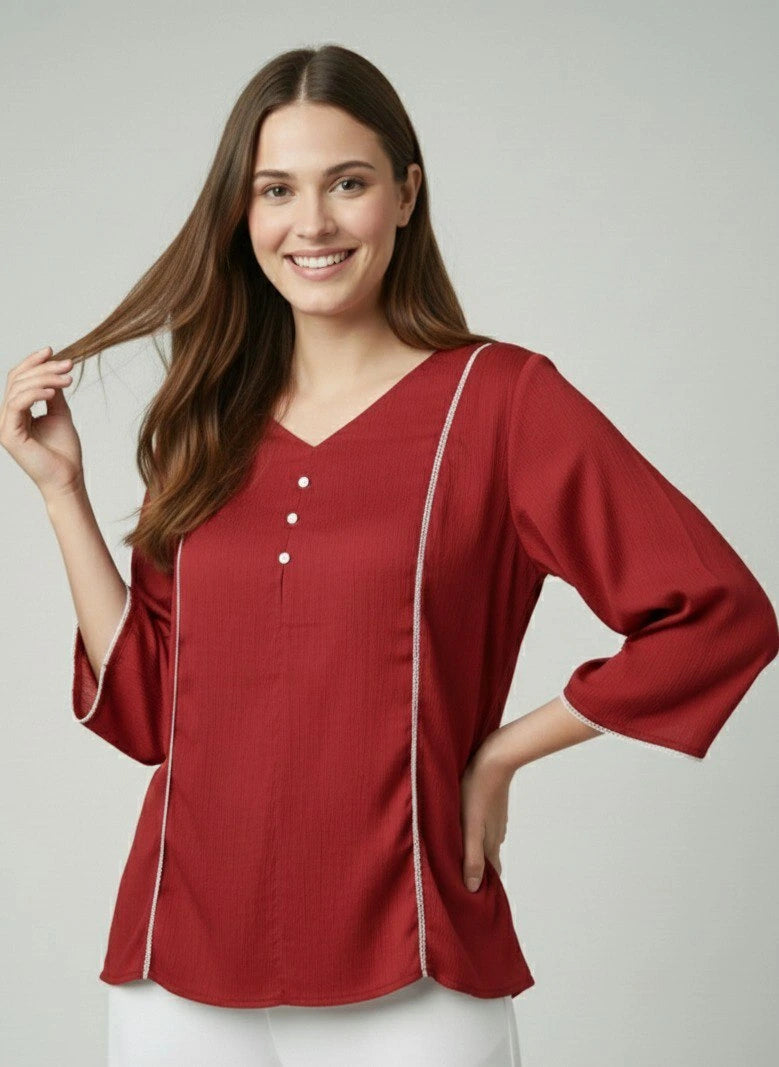 Woman wearing a red blouse with white trim on a plain background