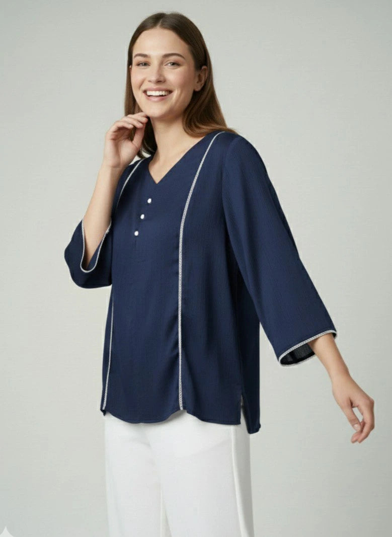 Woman wearing a navy blue blouse with white trim on a light gray background