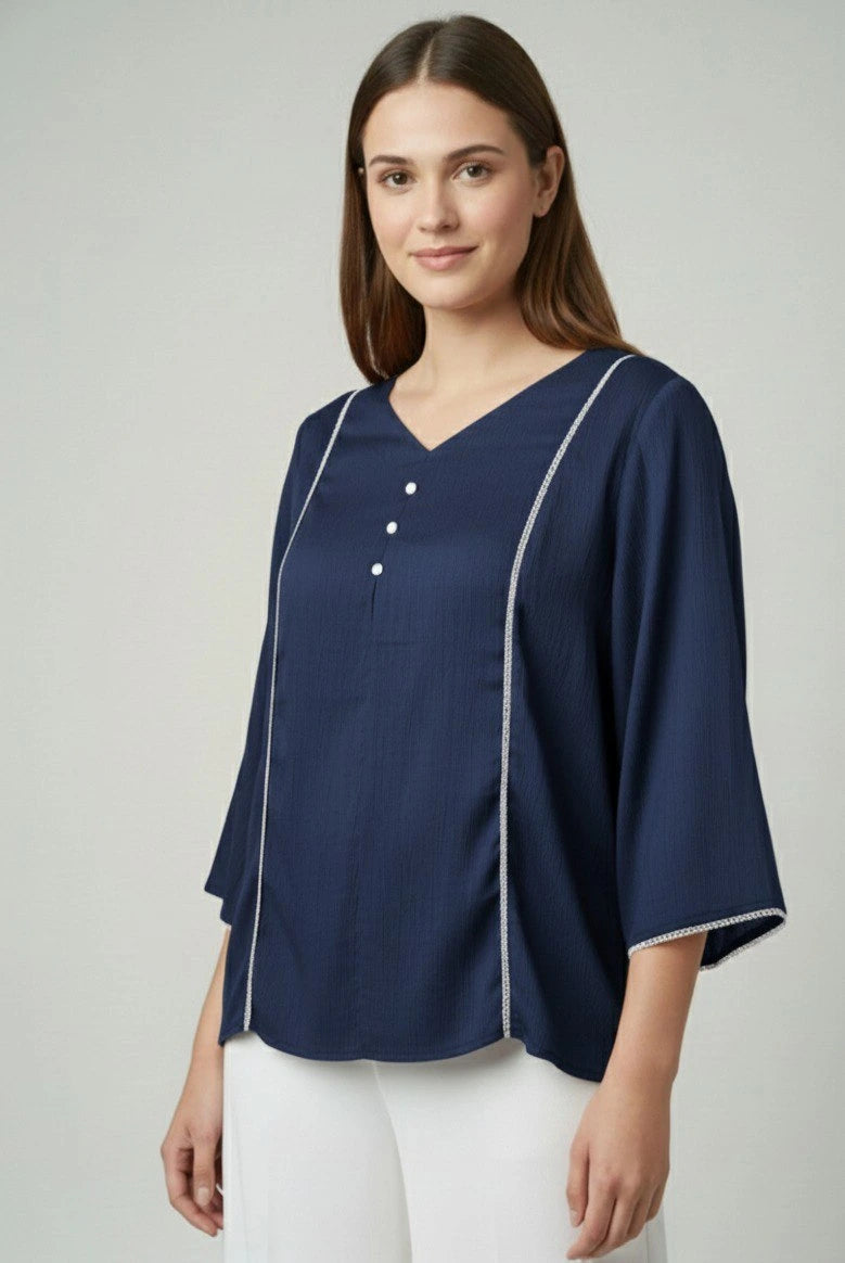 Woman wearing a navy blue blouse with white trim on a light gray background