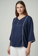 Woman wearing a navy blue blouse with white trim on a light gray background