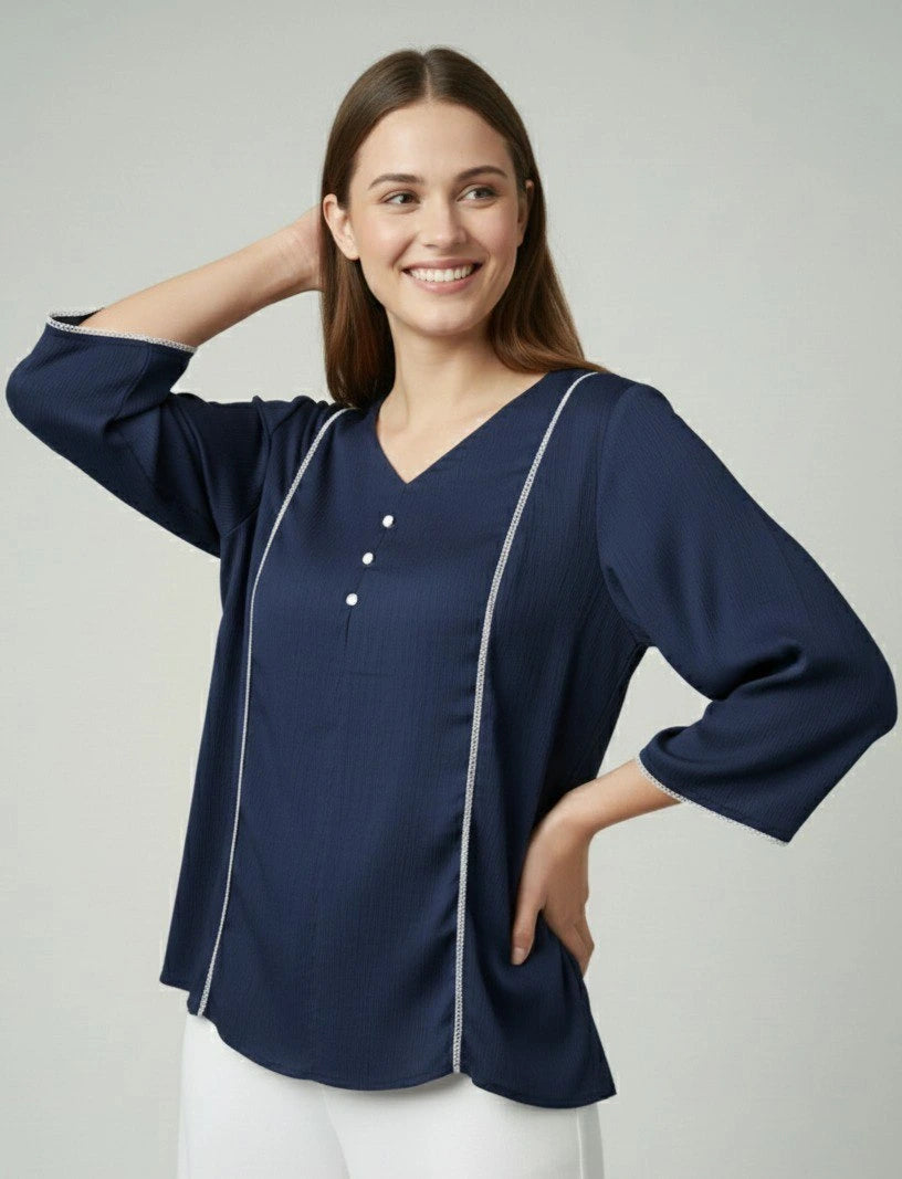 Woman wearing a navy blue blouse with white trim on a light gray background