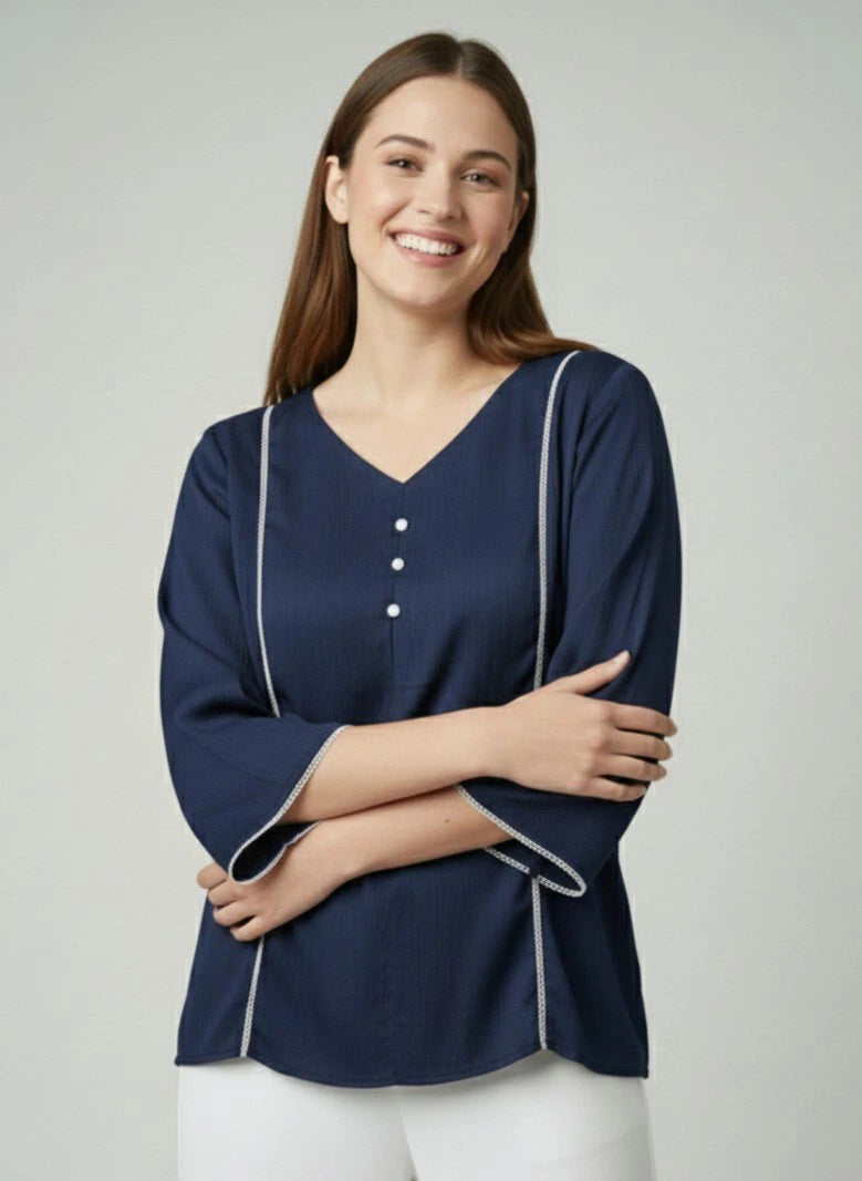 Woman wearing a navy blue blouse with white trim on a plain background