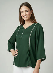 Woman wearing a green blouse with white trim on a gray background