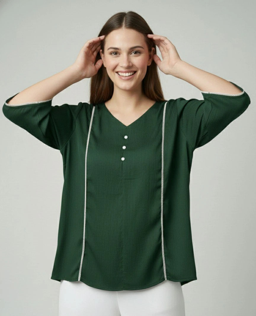 Woman wearing a green blouse with white trim on a plain background