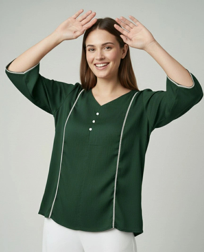 Woman wearing a green blouse with white trim on a plain background