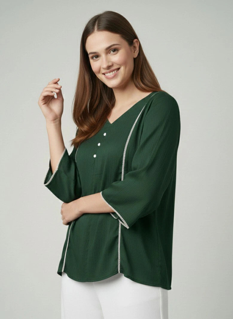 Woman wearing a green blouse with white trim on a plain background