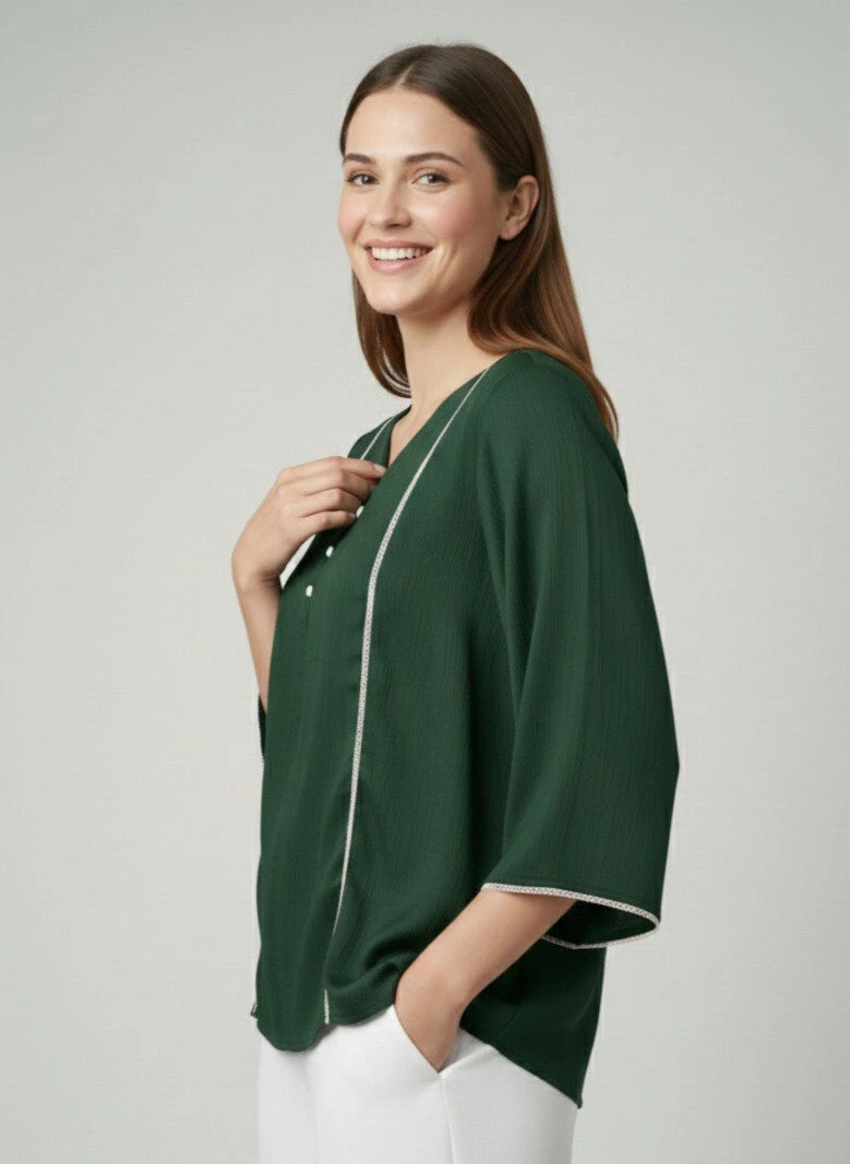 Woman wearing a green blouse with white trim on a plain background