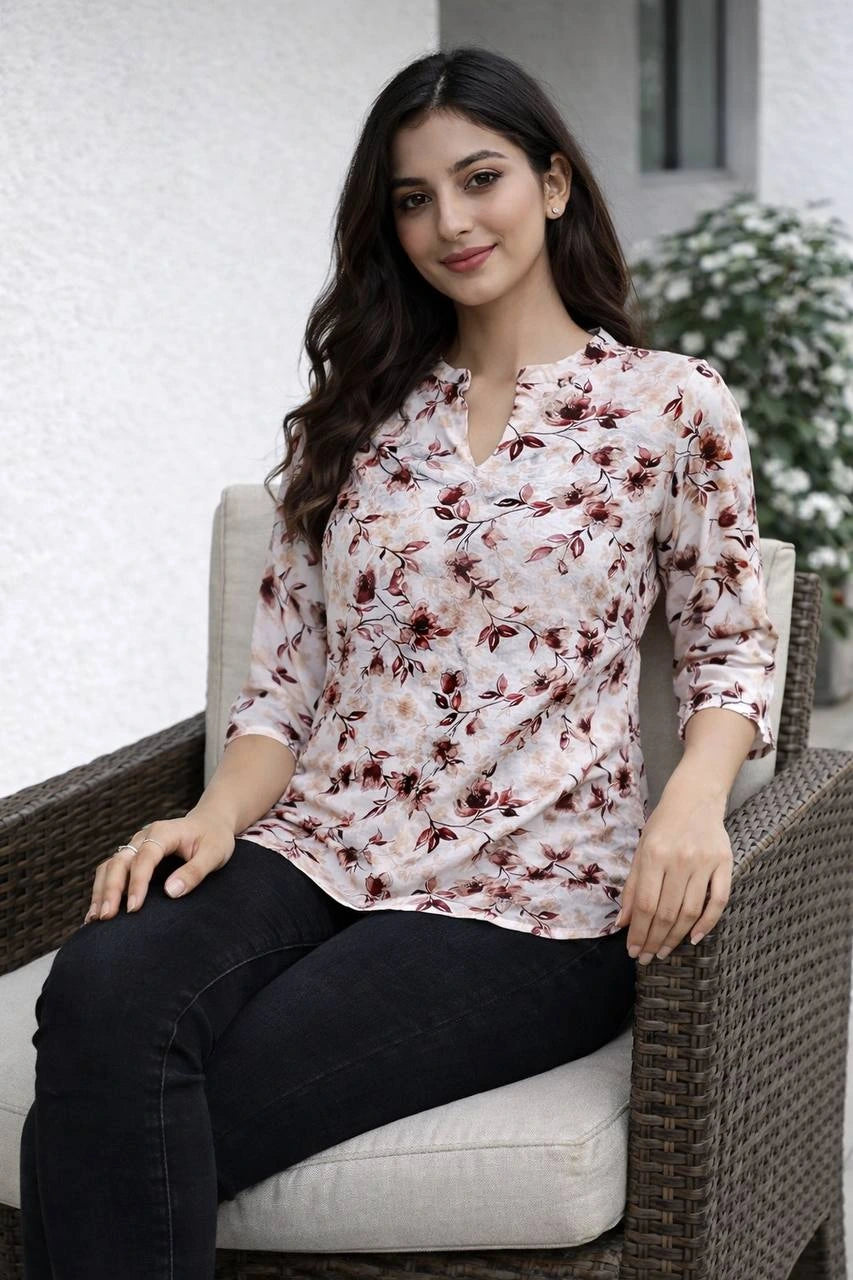 Woman wearing a floral blouse sitting on a chair outdoors.