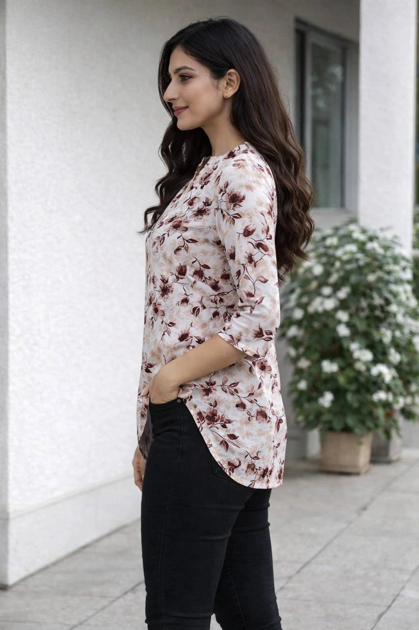 Woman wearing a floral blouse and black pants standing outdoors.