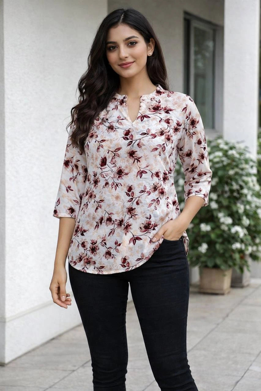 Woman wearing a floral blouse and black pants standing outdoors.