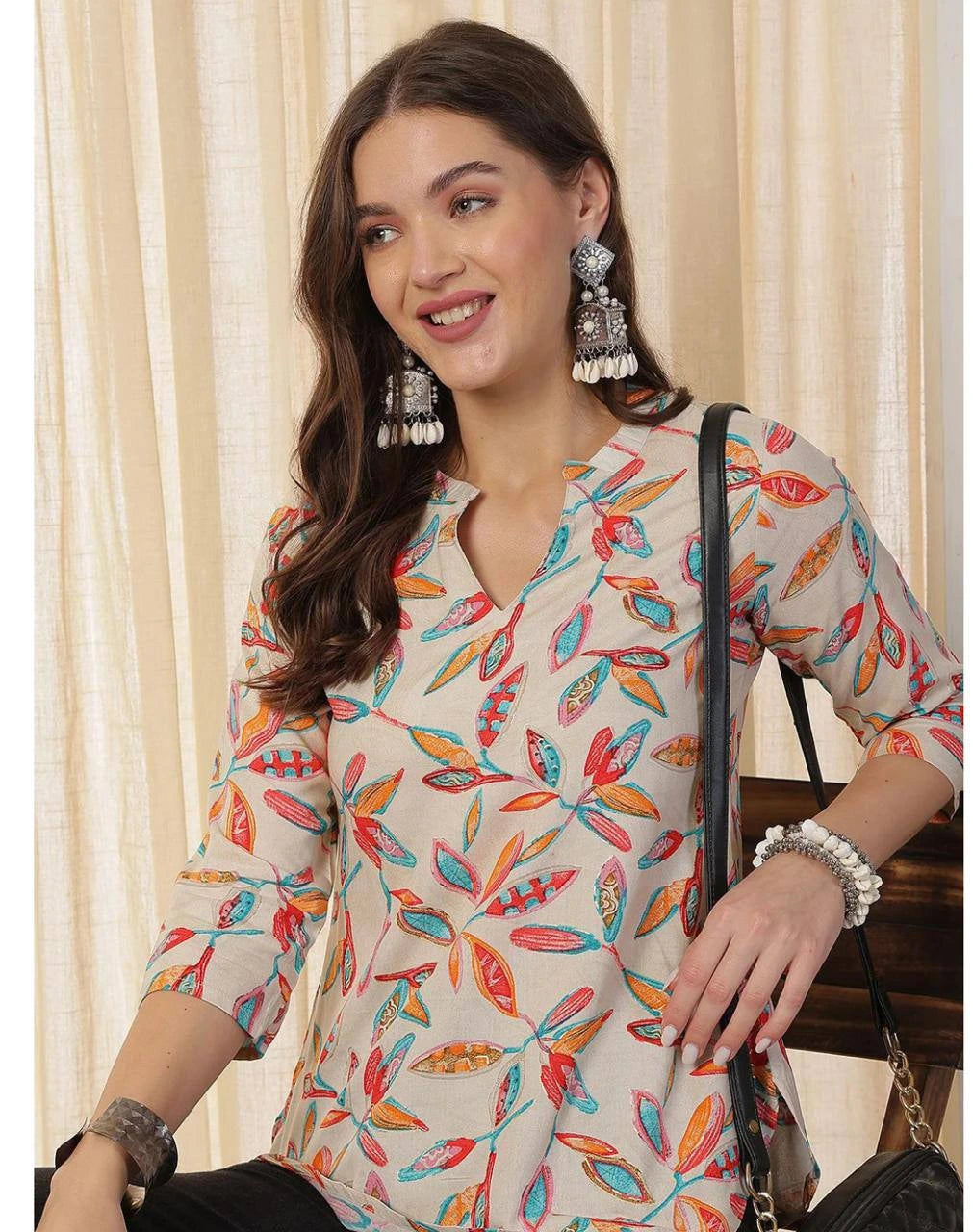 Woman wearing a colorful patterned top with a neutral background
