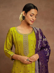 Woman wearing a green embroidered top and purple dupatta against a brown background