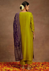 Woman wearing a green kurta with a purple dupatta on a brown background