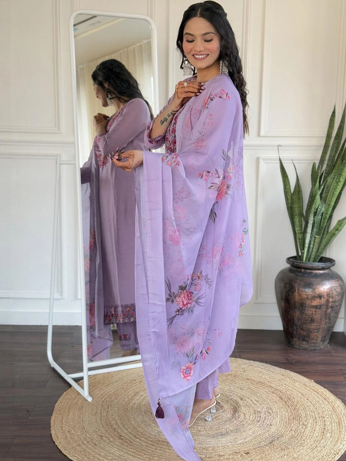Woman wearing a light purple floral outfit standing in front of a mirror.