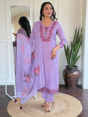 Woman in a lavender embroidered outfit standing in front of a mirror.