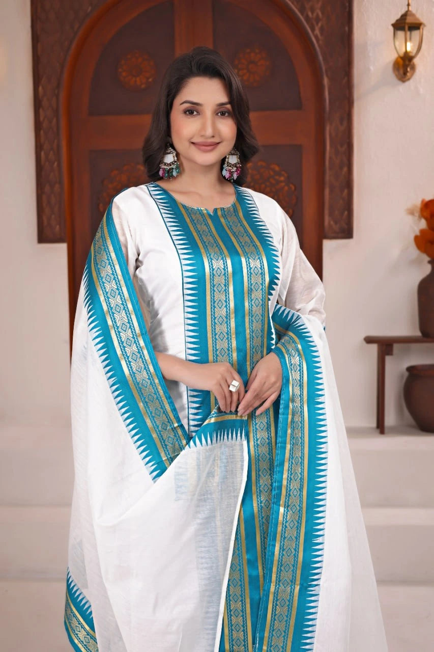 Woman wearing a white and blue traditional outfit with a decorative shawl indoors.