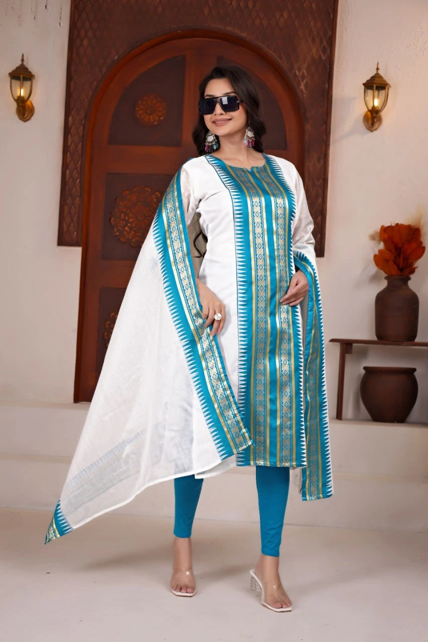 Woman wearing a white and blue traditional outfit with a patterned dupatta in a decorated room.