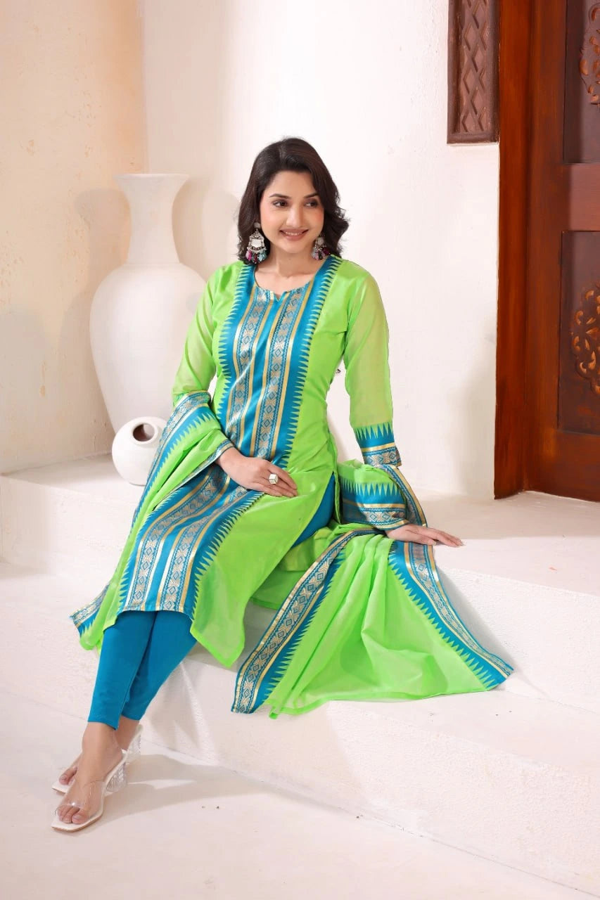 Woman in a green and blue traditional outfit sitting on a white couch.