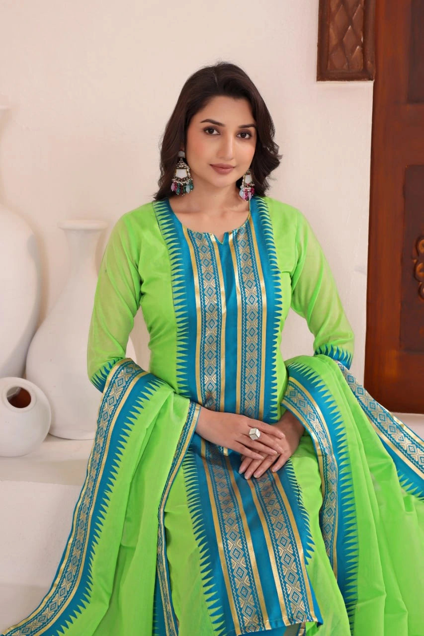Woman wearing a green and blue traditional outfit sitting on a white couch.