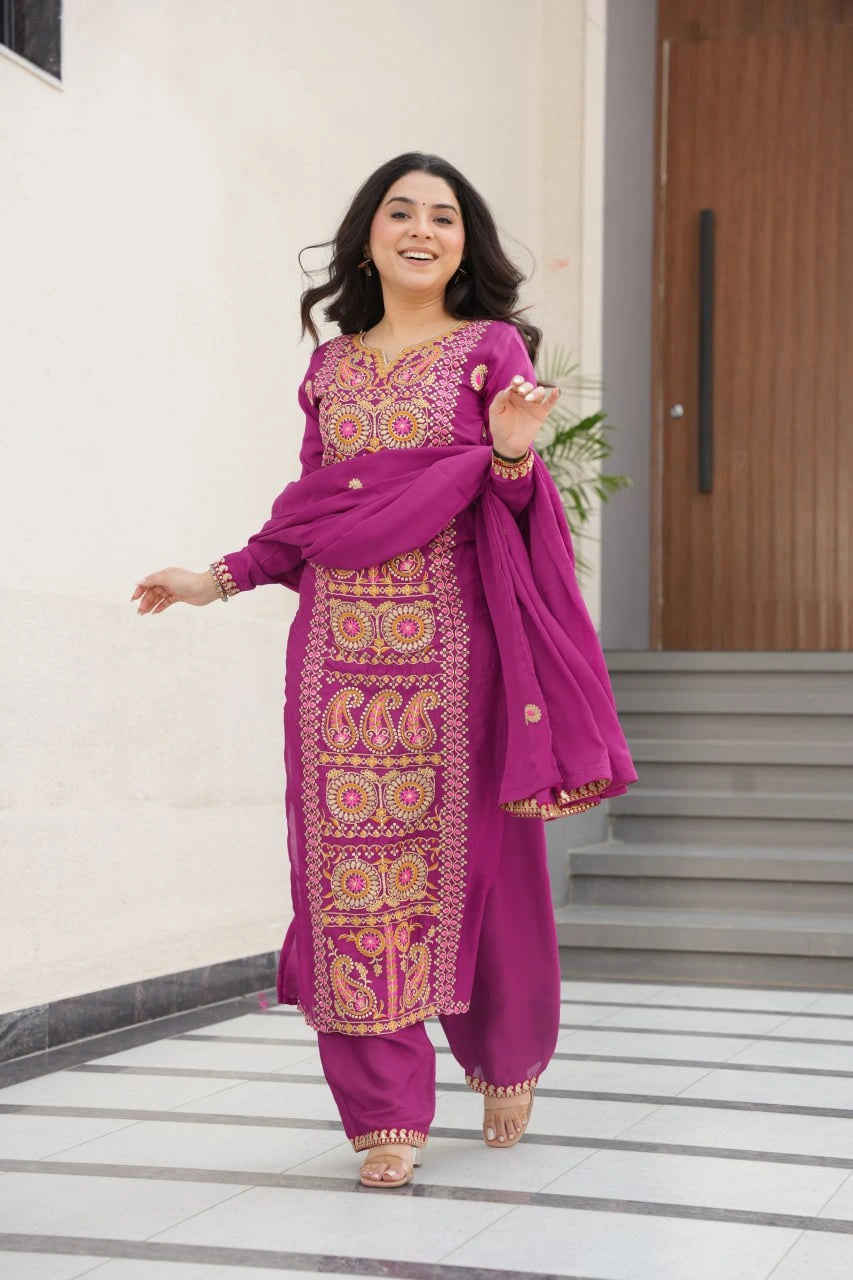 Woman in a vibrant purple traditional outfit with gold patterns standing on a staircase.