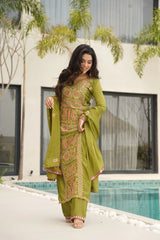 Woman in a green traditional outfit standing by a pool with plants in the background